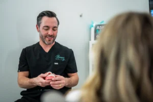 A dentist from Breez Dental is holding a dental model while explaining a procedure to a patient. The setting is a professional and welcoming dental office focused on patient education.