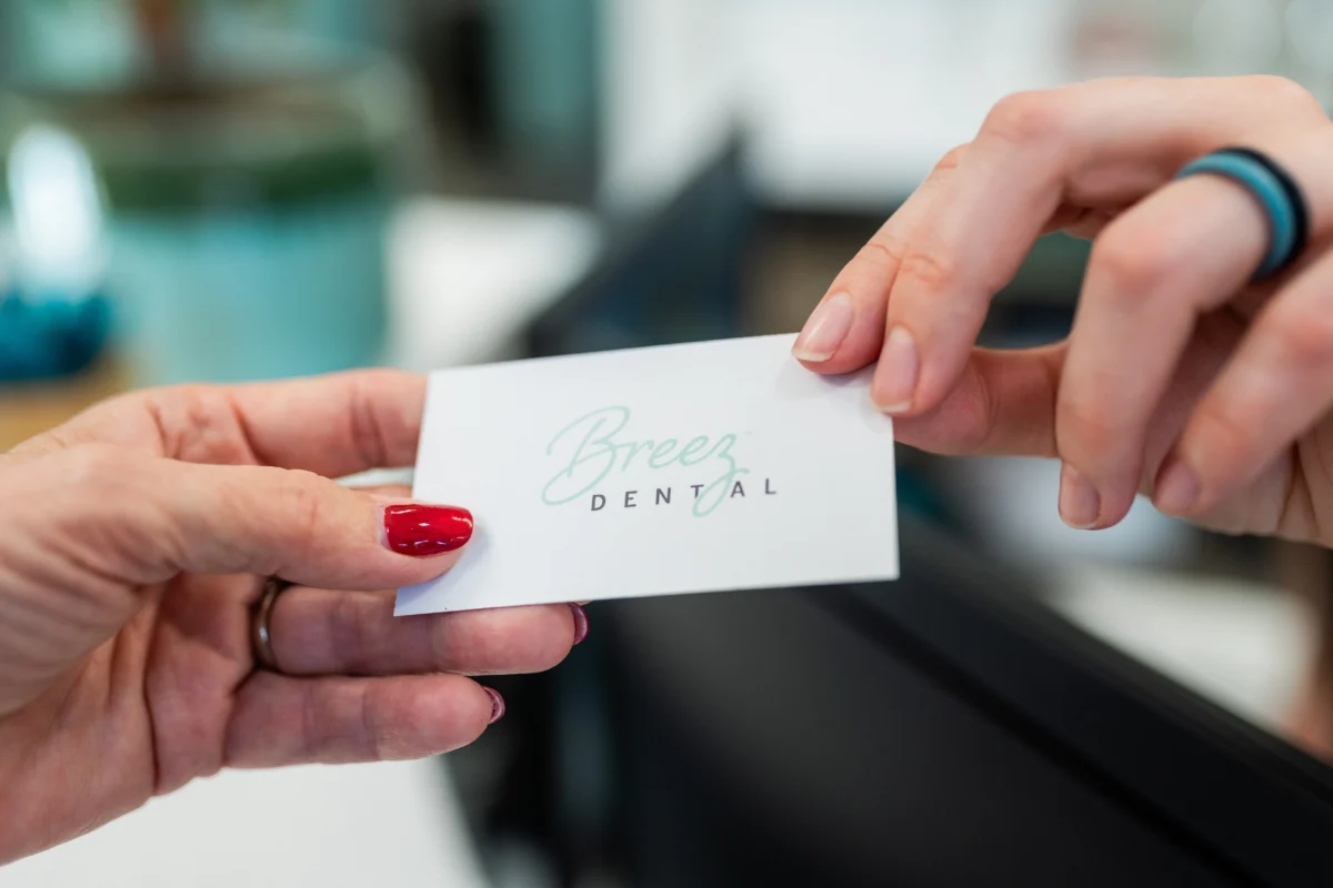 Close-up of hands exchanging a Breez Dental business card