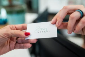 Close-up of hands exchanging a Breez Dental business card