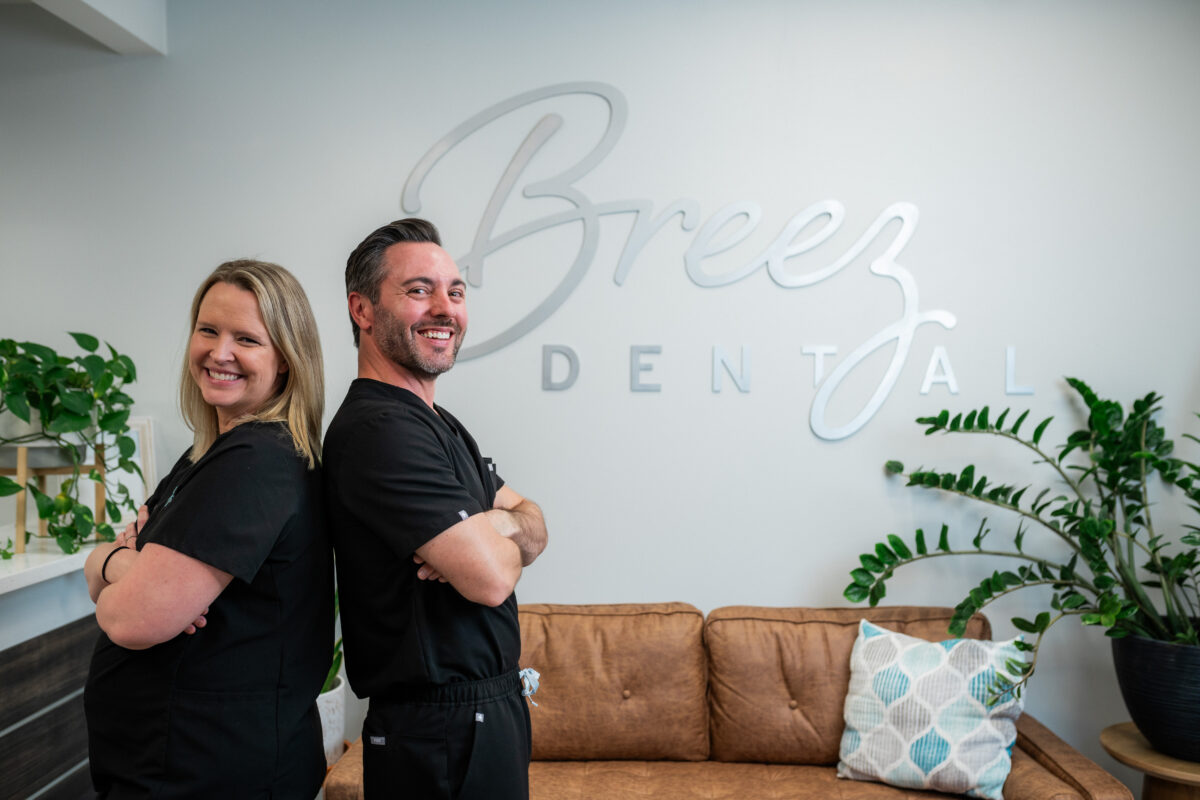 Charming doctor's smiling while crossing their arm's in the office of Breez Dental